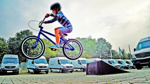 boy in black nutshell helmet on blue bmx bike having hangtime after taking off on ramp